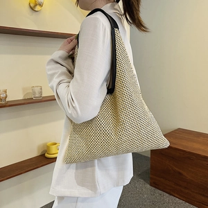 Large woven tote bag with wide black shoulder straps and minimalist straw texture style