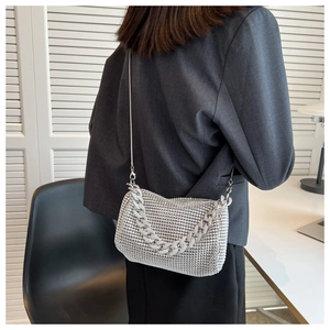 Detail of silver rhinestone crossbody bag with metal chain shown on model in office setting