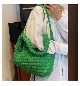 Mirror selfie showing vibrant green popcorn fabric cloud bag with textured pleats on shoulder