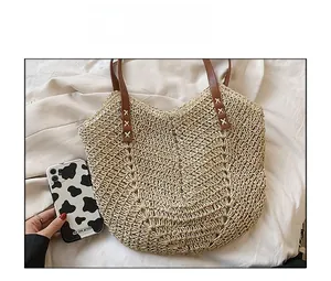 Detail view showing large woven straw tote bag capacity with brown faux leather straps