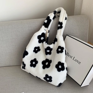 Close-up of black floral plush tote bag with soft texture on a grey sofa