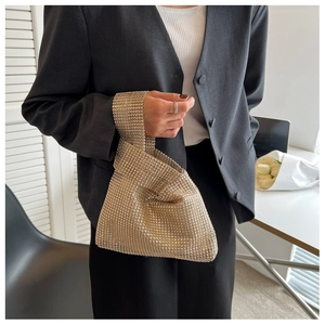 Close-up of elegant champagne gold rhinestone evening bag held by a model in a suit