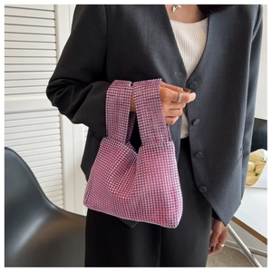 Detailed shot of a purple rhinestone handbag held by a model in a grey blazer