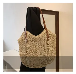 Detail of woven straw tote bag featuring herringbone texture and dark brown leather strap