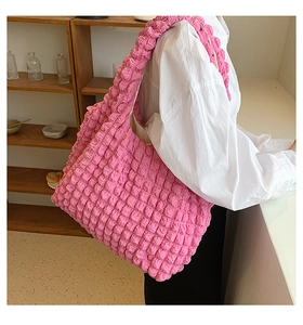 Detailed texture of a pink popcorn pleat tote bag on a model with white shirt
