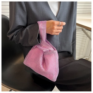 Detail view of the vibrant pink rhinestone mesh evening bag held by a model in a suit