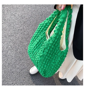 Detailed texture of green popcorn bubble fabric tote bag on a street style background
