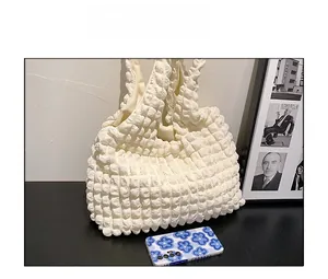 Close-up of cream textured cloud bag fabric next to a phone for size reference
