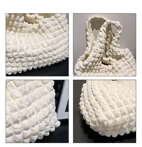 Detailed macro view of white popcorn fabric texture on a pleated shoulder tote bag