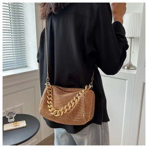 Close-up of golden brown rhinestone handbag featuring thick gold chain and luxury texture