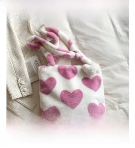 Detail of plush tote bag with white faux fur and pink heart patterns in a stylish setting