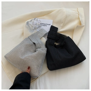 Close-up of knot evening bags in silver and black rhinestones on a beige suit