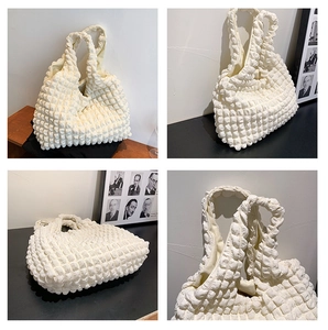 Detail view of the 3D bubble pleated texture on this soft cream canvas cloud bag