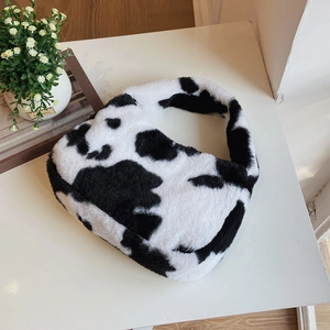 Close-up of soft cow print faux fur handbag on white surface with lifestyle props
