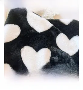 Detail shot of fluffy black plush tote bag with white heart pattern and soft texture