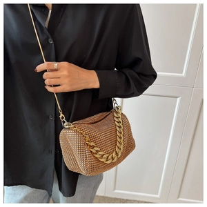 Champagne gold rhinestone cylinder handbag with elegant chain strap shown on black outfit
