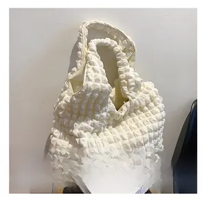 Detailed macro view of the white popcorn fabric texture on a soft cloud shoulder bag