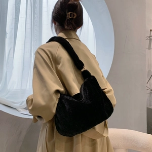Detail einer flauschigen schwarzen Kunstpelz-Schultertasche mit elegantem Trenchcoat