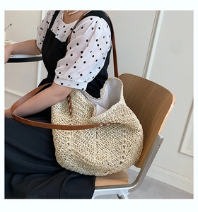 Detailed close-up of woven straw tote bag with brown leather straps and rivet accents