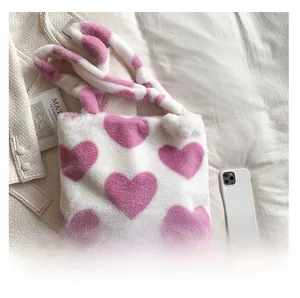 Detail of soft white faux fur handbag featuring large pink plush heart patterns