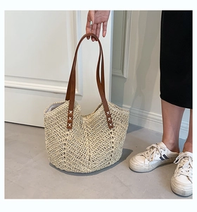 Detailed close-up of woven straw texture and brown leather handles on a summer beach tote