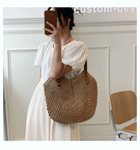 Fashionable woven straw shoulder bag with brown leather straps for summer beach vacations