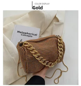Detail of a gold crossbody bag featuring sparkling rhinestones and a chunky metal chain handle