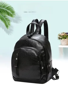 Detail of black pebbled leather backpack showing dual zippers and silver metal hardware