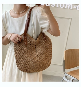 Detailed view of bohemian straw bag featuring V-shape woven texture and brown leather strap