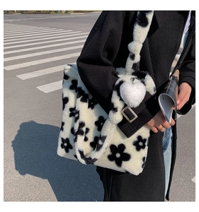 Close-up of fluffy black and white floral plush tote bag with a white heart charm pendant
