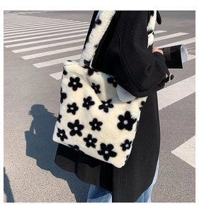 Detail of soft black and white plush tote bag with flower pattern on a sunny street