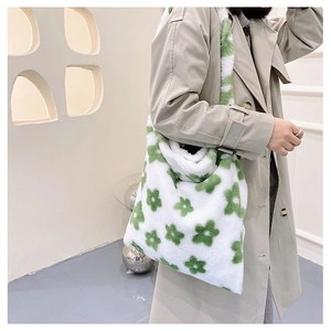 Detail of soft white plush tote bag featuring green floral patterns and wide shoulder strap
