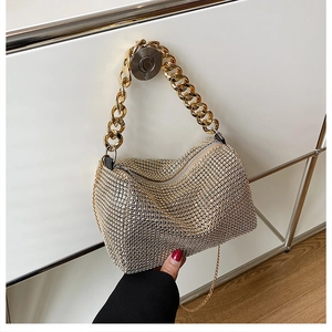 Detail of elegant gold rhinestone handbag featuring a thick gold chain handle and luxury texture