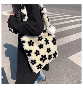 Detail of plush tote bag featuring floral print and soft pompom pendant accessory