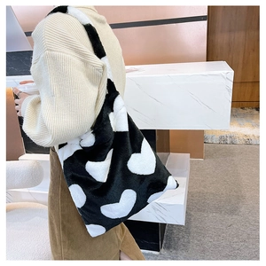 Detail of soft plush tote bag featuring large white heart pattern on black faux fur fabric