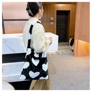 Detail of plush tote bag with black and white heart pattern shown on a shoulder