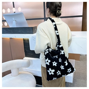 Detail of plush black and white flower tote bag shown on model in a modern interior