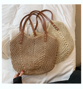 Macro detail of large straw tote bag with wave pattern weaving and brown leather handles