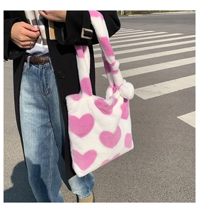 Outdoor street style view showing the soft plush texture and pink heart patterns on the bag
