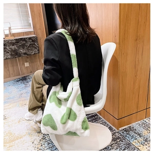 Detailed texture of white plush tote bag with green heart patterns on female shoulder