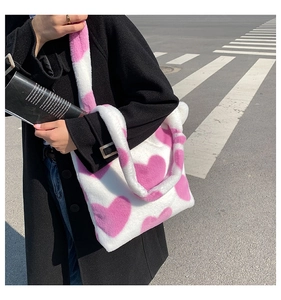 Close-up of white plush faux fur tote bag featuring soft pink heart patterns