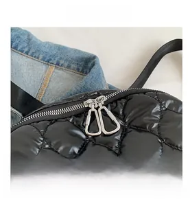 Detail of trendy silver metal double zippers on a black quilted shiny nylon backpack