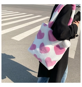 Plush shoulder bag with pink hearts shown on model in black wool coat for autumn style