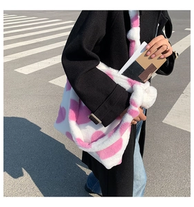 Detail view of white plush tote bag with pink hearts and wide shoulder strap