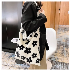 Detail view of large plush tote bag with black and white floral pattern on a shoulder strap