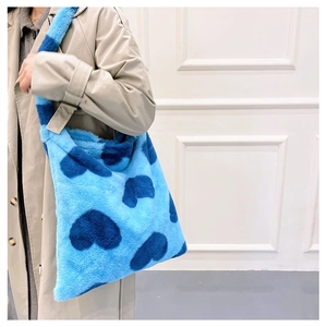 Detail view of a large fluffy faux fur tote bag in light blue with dark blue heart patterns