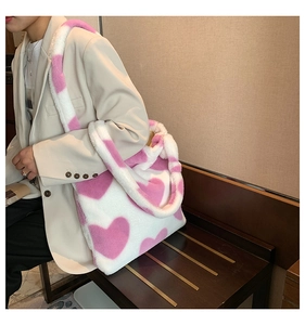 Detail view of large pink heart pattern on white plush tote bag with furry handle