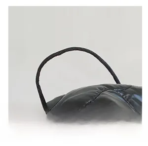 Detail of the glossy black quilted nylon handbag featuring slim rounded carry handles