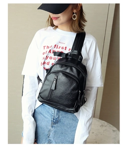 Detailed view of a black washed PU leather sling bag with multiple zip pockets on model