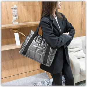 Detail view of deep grey quilted tote bag with metallic glossy finish on a shoulder strap